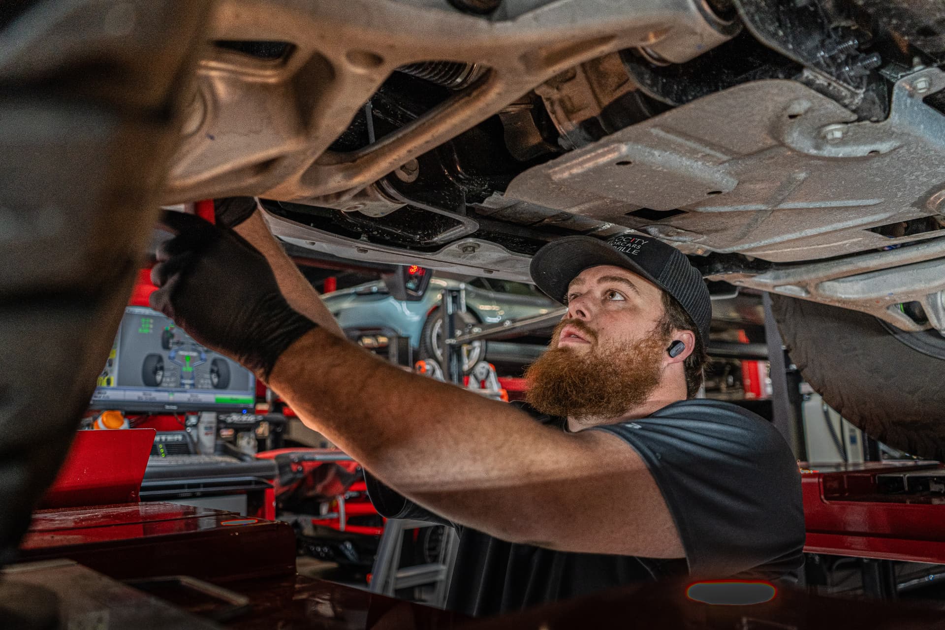 Velocity technician performing repair work beneath a lifted vehicle