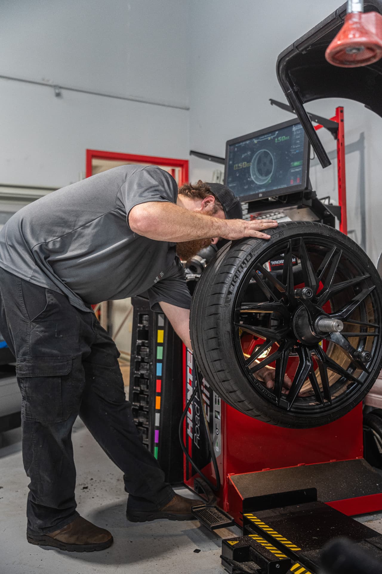 Velocity Motorcars technician mounting a performance tire on a Hunter road force balancer